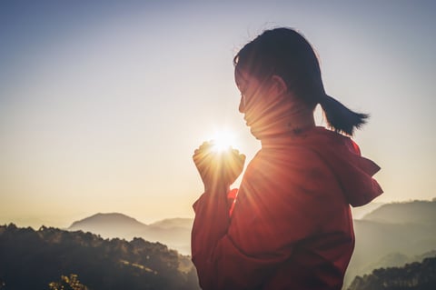 Woman praying on mountain at sunset